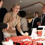 　福島県の郷土玩具「赤べこ」を前に笑顔を見せる来場者＝２１日、スイス東部ダボス（共同）