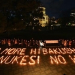 　核兵器禁止条約の発効から５年を迎え、キャンドルを並べて作られた「ＮＯ　ＭＯＲＥ　ＨＩＢＡＫＵＳＨＡ」などの文字。後方は原爆ドーム＝２２日夕、広島市中区の平和記念公園