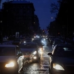 　停電で真っ暗となった道を進む乗用車＝２５日、キーウ（ロイター＝共同）