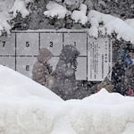 　雪でかすむ衆院選候補者のポスター掲示板＝２６日、札幌市