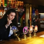 　酒を注ぐパブの従業員＝２０２３年１月、英国ケンブリッジ（ロイター＝共同）