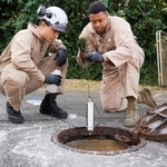 　白い泡が出ているのが見つかったマンホールを調査する米軍関係者＝２９日午後、沖縄県宜野湾市