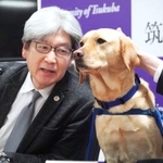 　ファシリティドッグとして訓練中の「ミコ」と記者会見する平松祐司筑波大病院長＝２９日、茨城県つくば市
