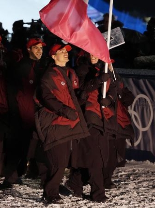 　ミラノ・コルティナ冬季五輪の開会式で、旗手を務めるカナダのミカエル・キングズベリー（中央）＝６日、イタリア・リビーニョ