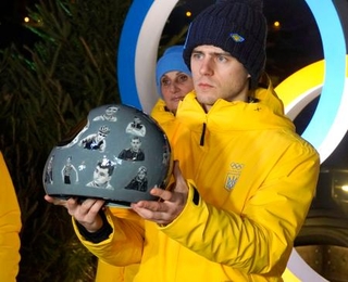 　ロシアの攻撃で犠牲となったアスリートたちの顔写真を張ったヘルメットを手にするスケルトン男子ウクライナ代表のウラジスラフ・ヘラスケビッチ＝１０日、コルティナダンペッツォ（共同）