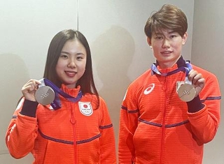 　帰国し、フィギュアスケート団体で獲得した銀メダルを掲げるアイスダンスの吉田唄菜（左）と森田真沙也＝１１日、羽田空港