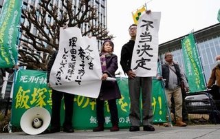 　「飯塚事件」の再審開始が認められず、福岡高裁前で「不当決定」などと書かれた紙を掲げる支援者ら＝１６日午後