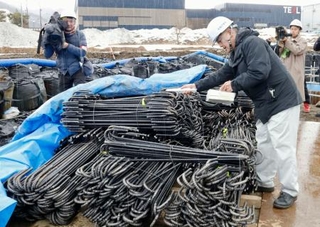 　「クリアランス金属」を再利用した鉄筋の放射線量を測定する担当者（右）＝１８日午後、福井県南越前町