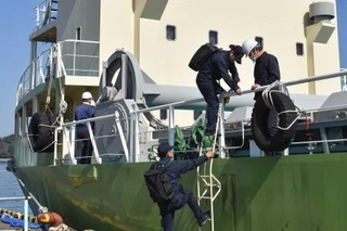 　貨物船に立ち入る運輸安全委員会の船舶事故調査官＝２２日午後、三重県鳥羽市