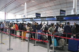 　春節に合わせた大型連休の初日、北京首都国際空港で日本便などをあつかうカウンターにならぶ人たち＝１５日（共同）
