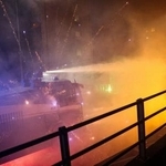 　五輪開催の抗議で、デモ隊の花火に対し、放水する警官隊＝７日、ミラノ（ロイター＝共同）