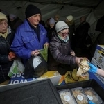 　７日、ウクライナ・キーウで、政府が運営する住民支援テントで食事を受け取る人たち（ロイター＝共同）