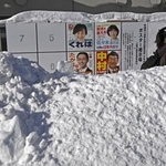 　雪の中に立つ衆院選のポスター掲示板。手前の道路には人の背丈ほどの高さに雪が積み上げられていた＝８日午前、北海道小樽市