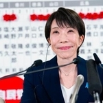 　当確者の名前のバラの前で、メディアのインタビューに笑顔で答える自民党総裁の高市首相＝８日午後１０時３分、東京・永田町の党本部