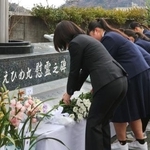 　えひめ丸事故から２５年となり、「追想の日」式典で慰霊碑に献花する宇和島水産高の生徒ら＝１０日午前、愛媛県宇和島市