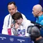 　男子ＳＰの得点を確認し、亡き両親の写真に額をつけるマキシム・ナウモフ＝ミラノ（共同）