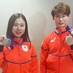 　帰国し、フィギュアスケート団体で獲得した銀メダルを掲げるアイスダンスの吉田唄菜（左）と森田真沙也＝１１日、羽田空港