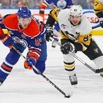 　ＮＨＬの試合で競り合うペンギンズのシドニー・クロスビー（右）とオイラーズのコナー・マクデービッド＝１月、エドモントン（イマジンイメージズ・ロイター＝共同）