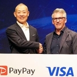 　記者会見で米ビザの幹部と握手するペイペイの中山一郎社長（左）＝１２日午後、東京都内