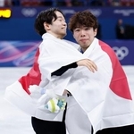 　日の丸をまとって抱き合う、男子で銀メダルの鍵山優真（左）と銅メダルの佐藤駿＝ミラノ（共同）