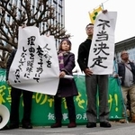 　「飯塚事件」の再審開始が認められず、福岡高裁前で「不当決定」などと書かれた紙を掲げる支援者ら＝１６日午後