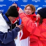 　スノーボード女子スロープスタイルで優勝した深田茉莉（右）から金メダルをかけてもらう佐藤康弘コーチ。中央は練習仲間で五輪王者の蘇翊鳴＝１８日、イタリア・リビーニョ（共同）