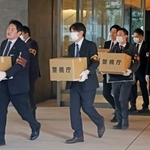 　家宅捜索で押収物を運び出す警視庁の捜査員ら＝２０日午前、東京都港区