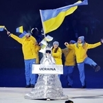 　ミラノ・コルティナ冬季五輪の開会式で、プラカードを持ってウクライナ選手団を先導するロシア人のクチェロワさん＝６日、イタリア・ミラノ（共同）