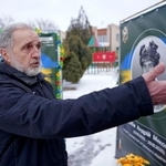 　息子の遺影の前で取材に応じるミコラ・シロババさん＝２３日、スラビャンスク（共同）