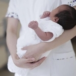 　病院で助産師に抱かれる新生児
