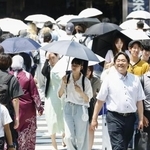 　日傘を差して歩く人たち＝２０２５年７月、東京都新宿区