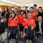 　見送りに来た人たちと笑顔で記念写真に納まる車いすカーリング混合ダブルスの小川亜希（手前左）、中島洋治（同右）組＝２８日、羽田空港