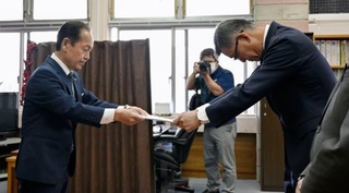 　米軍ヘリの緊急着陸を受け、防衛省沖縄防衛局の村井勝局長（右）に抗議文書を手渡す沖縄県名護市の渡具知武豊市長＝９日午前、名護市役所