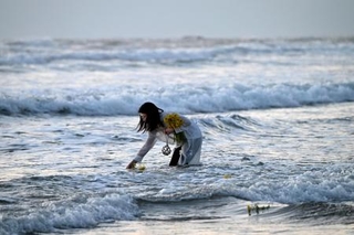 　東日本大震災で被災した福島県いわき市の薄磯海岸で、花を手向ける女性＝１１日午前５時４７分