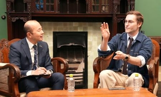 　長崎市の鈴木史朗市長（左）と対談するクレイグ・モドさん＝１９日午後、長崎市