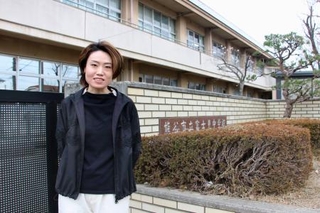 　通級指導教室の支援員として働いた母校の前に立つ新井麻衣良さん＝埼玉県熊谷市