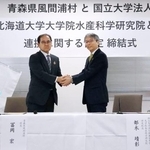 　協定締結式で握手する、青森県風間浦村の冨岡宏村長（左）と北海道大大学院水産科学研究院の都木靖彰研究院長＝３日午前、北海道函館市