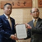 　滋賀県税制審議会から中間答申を受け取る三日月大造知事（左）＝４日午後、滋賀県庁