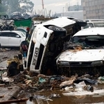 　７日、ケニア・ナイロビで、豪雨の影響で大破した車両の近くを歩く女性（ロイター＝共同）