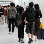 　中東情勢の悪化を受け、政府手配の民間チャーター機でオマーンから成田空港に到着した人たち＝８日午後８時１分