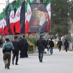 　９日、イラン・テヘランで、国旗や殺害されたハメネイ師のポスターが掲げられた通りを歩く人（ＷＡＮＡ提供・ロイター＝共同）