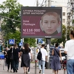 　２０２３年７月、子どもの捜索に取り組むＮＧＯが大型モニターに流した、行方不明者の情報提供を呼びかける広告＝キーウ中心部（共同）