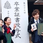 　長男泰介さんの写真と卒業証書を手に、泰介さんの友人らと記念写真に納まる大間圭介さん＝１３日午後、金沢市