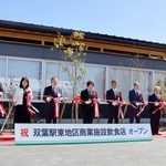 　ＪＲ双葉駅前に完成した商業施設のオープニングセレモニーで、テープカットする伊沢史朗町長（左から４人目）ら＝１４日午前、福島県双葉町