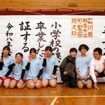 　大きな紙でできた「卒業証書」の前で、記念写真に納まる川原脩伸さん（右端）ら＝２１日午後、石川県輪島市の町野小