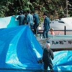 　辺野古沖で転覆した船「平和丸」を実況見分する海保の係官ら。奥は「不屈」＝２２日午前、沖縄県名護市