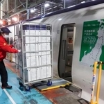 　荷物専用新幹線から積み荷を降ろす作業員＝２３日午後、東京都北区の車両基地
