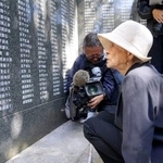 　米軍上陸から８１年となり、犠牲者の名前が刻まれた石碑を見つめる女性＝２６日午前、沖縄県・座間味島