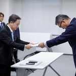 　防衛省沖縄防衛局の村井勝局長（右）に意見書を手渡す沖縄県宜野湾市議会の呉屋等議長＝２６日午後、嘉手納町