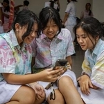 　友人とスマートフォンでＴｉｋＴｏｋを見る１４歳の少女（左）＝２７日、インドネシア・ジョクジャカルタ（ゲッティ＝共同）